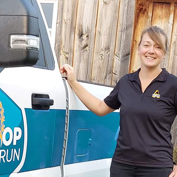 Jennifer Wubs standing next to her Co-op Embrun pick-up truck making farm visits. 