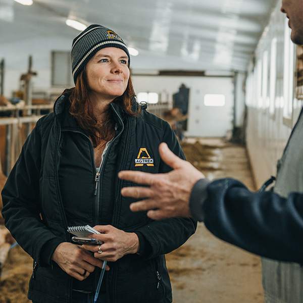 Julie Lortie standing in a barn speaking with a farmer.