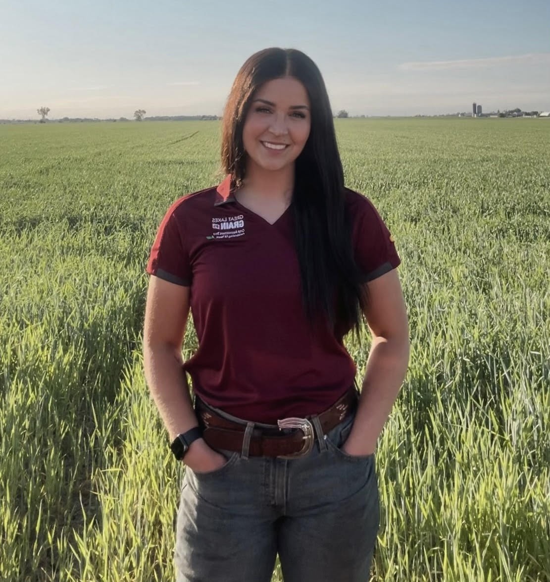 Sydney Lemoyre debout dans un champ de soja avec une tablette parlant avec un agriculteur.